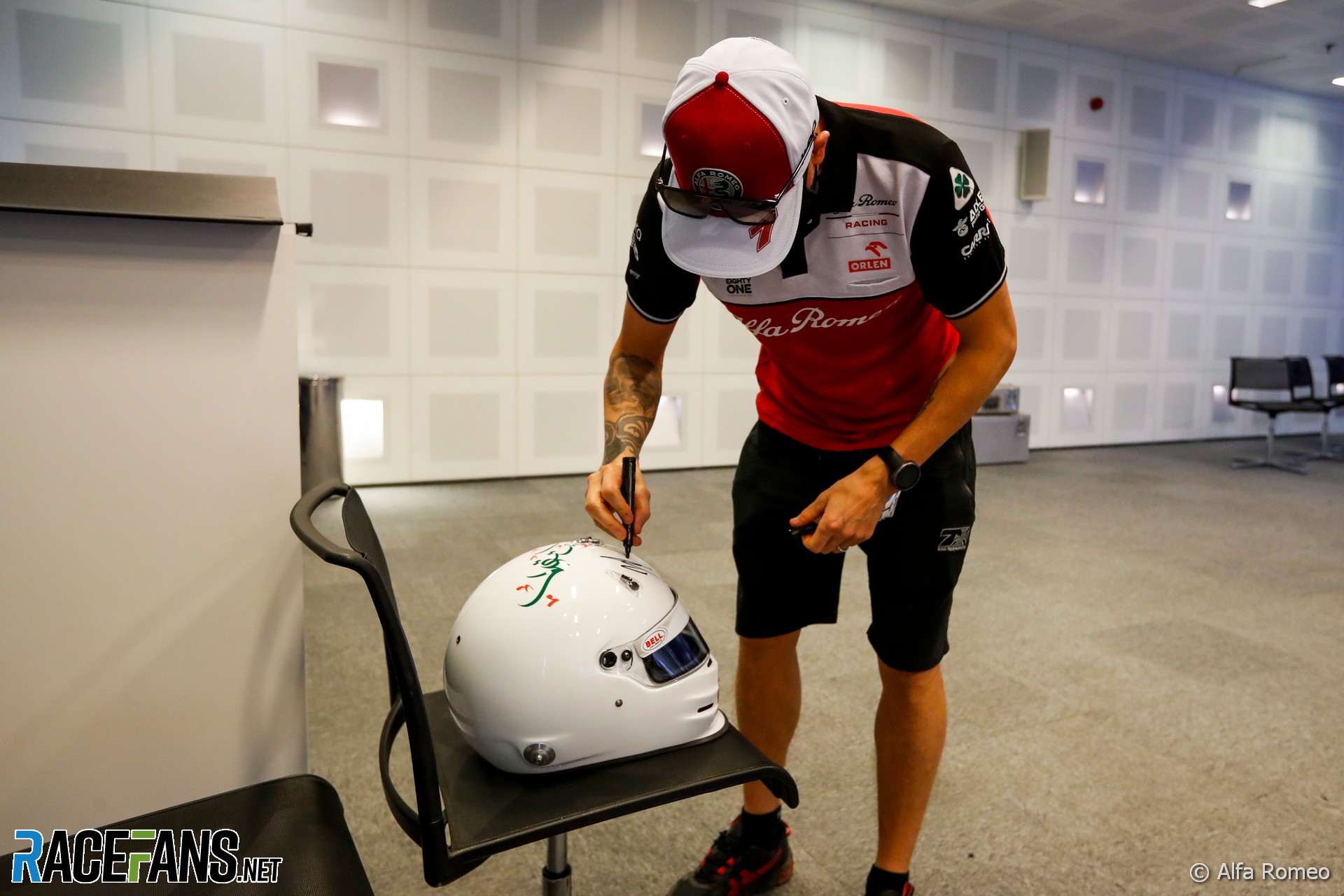 Kimi Raikkonen signs a helmet for outgoing FIA president Jean Todt