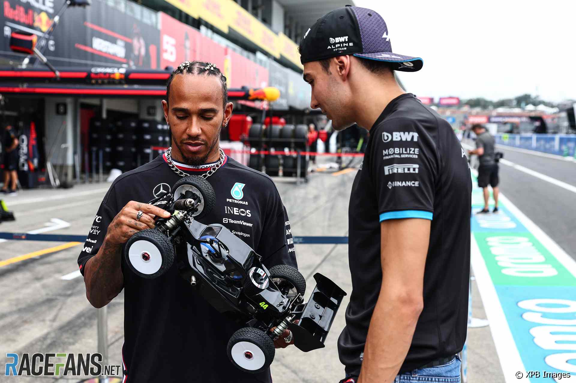 Lewis Hamilton and Esteban Ocon inspect a remote control car